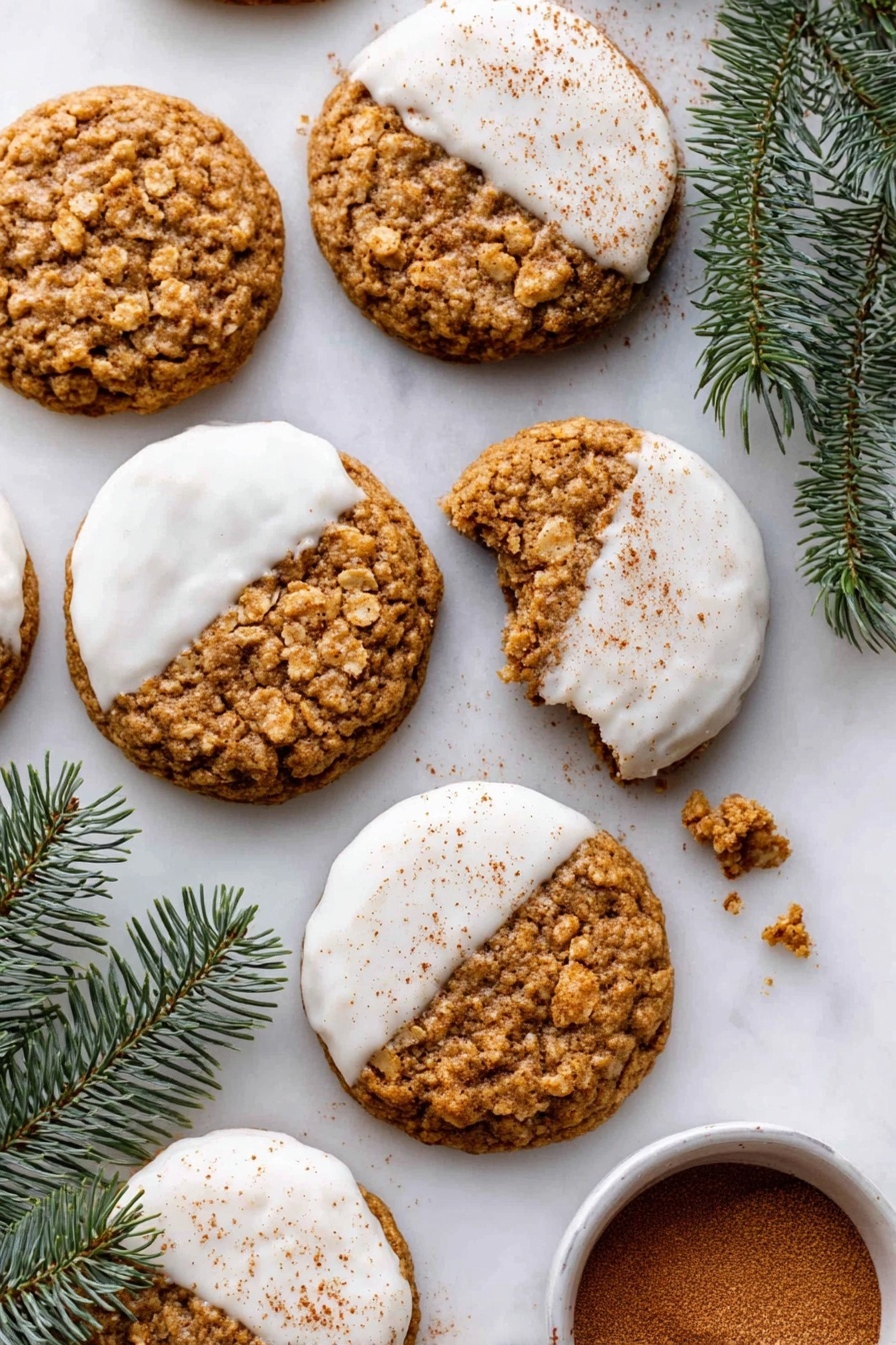 The image shows round oatmeal cookies, some dipped halfway in white icing that is smooth and slightly glossy, with a light sprinkle of cinnamon powder on top of the icing. The cookies have a golden brown, rough, and chunky texture from the oats with some broken cookie pieces around. They are arranged on a white marbled surface with a few green pine branches in the corners, and a small white bowl with cinnamon powder sits near the bottom right. The composition is bright with soft natural light. Photo taken with an iphone --ar 2:3 --v 7