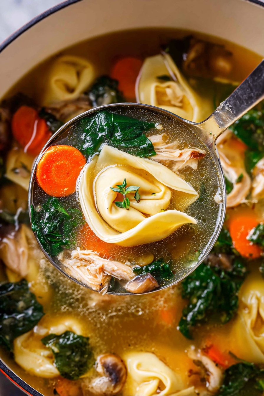 A white bowl filled with clear broth layered with bright orange carrot pieces, deep green spinach leaves, light green celery slices, and beige mushrooms. Floating on top are pale yellow tortellini pasta with red pepper flakes sprinkled over them. There are pieces of light brown shredded chicken and some fresh green herbs scattered throughout, with two thin pale yellow lemon slices placed on the right side of the bowl. The bowl is set on a white marbled surface with scattered fresh green herbs and a halved lemon nearby. Photo taken with an iphone --ar 2:3 --v 7